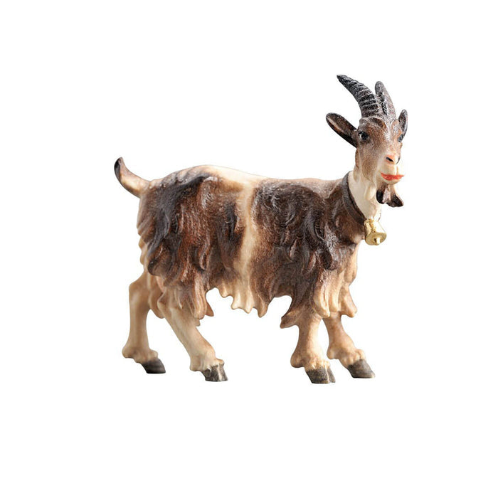 Hand-carved PEMA Kostner nativity goat with bell collar, shaggy brown and white coat, and curved horns, looking right.