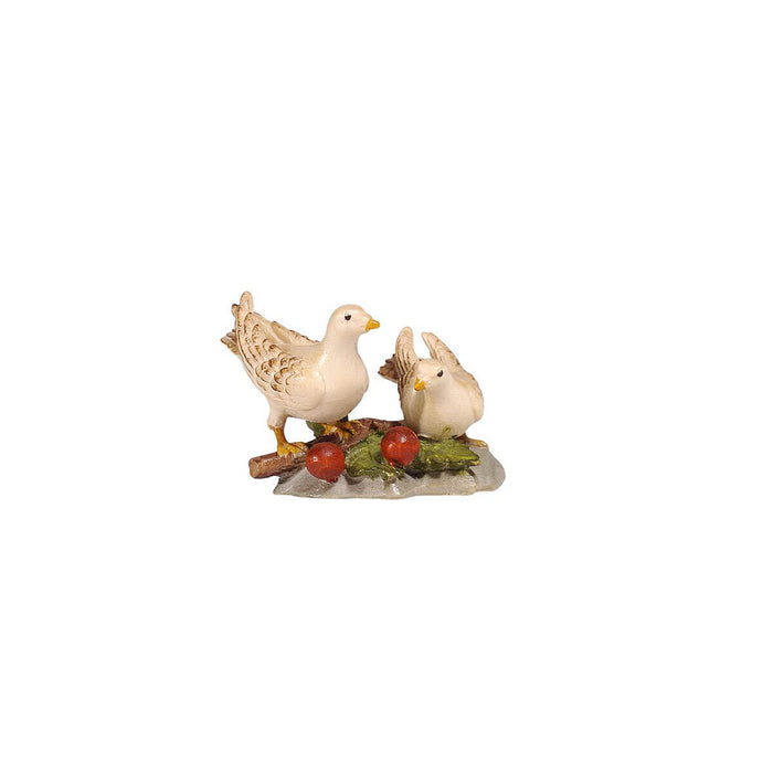 Hand-carved PEMA Kostner nativity pair of white doves, one standing and one sitting, resting on twigs with red berries and green leaves, crafted in Val Gardena, Italy.
