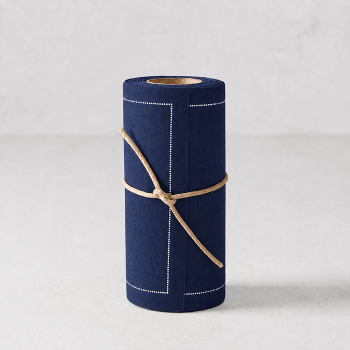 Roll of 50 petrol blue cotton cocktail napkins with white stitched border detail, tied with twine.