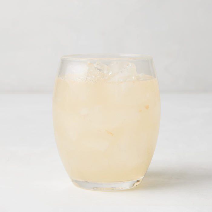 Clear 18oz Poolside Acrylic Stemless Wine Glass filled with a light-colored drink and ice.