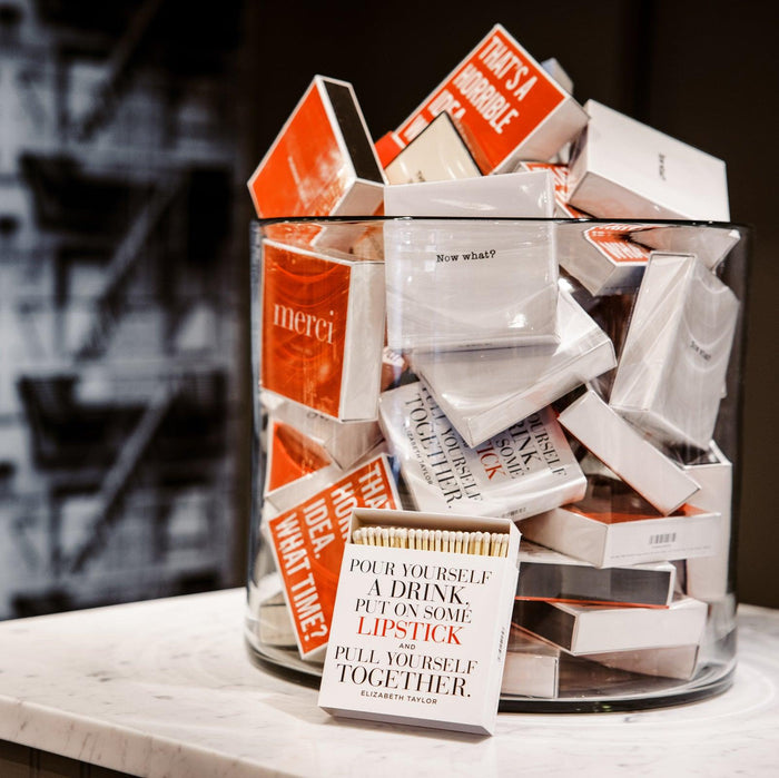 White and orange "Pour Yourself a Drink" boxed matches with long sticks in a glass jar.