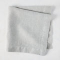 Rain HG Signature hand-dyed light grey linen napkin, 22-inch square, folded.