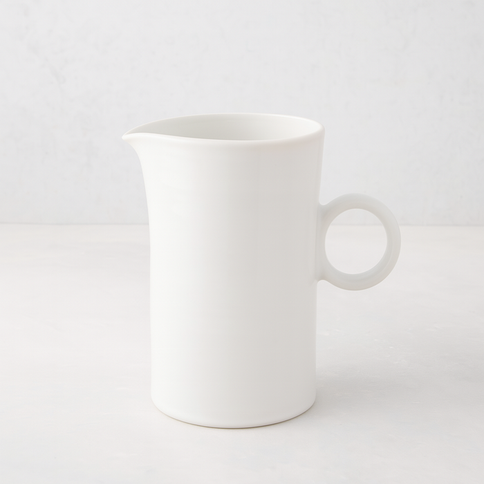 Creamy white ceramic pitcher with a simple ring handle and spout.