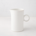 Creamy white ceramic pitcher with a simple ring handle and spout.