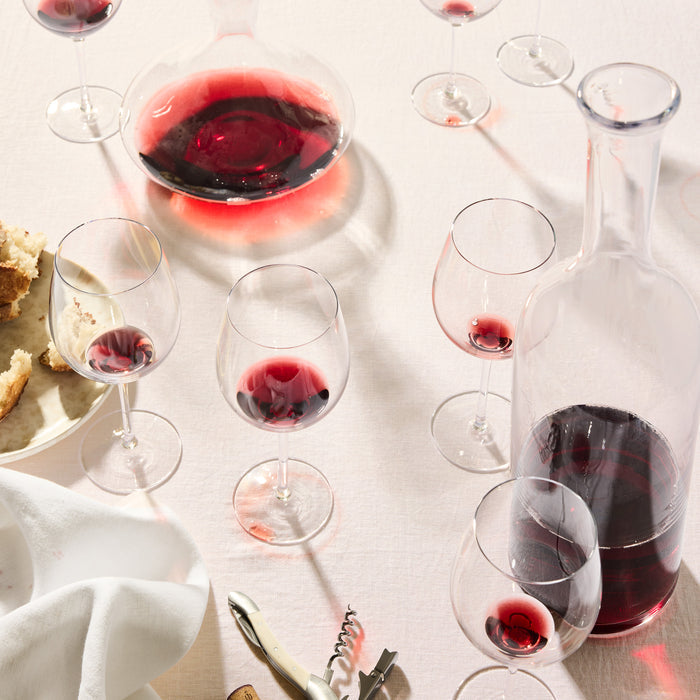 Romeo Scissor-Cut Glass Wine Carafe, 17.5"H, filled with red wine on a light tablecloth with glasses.