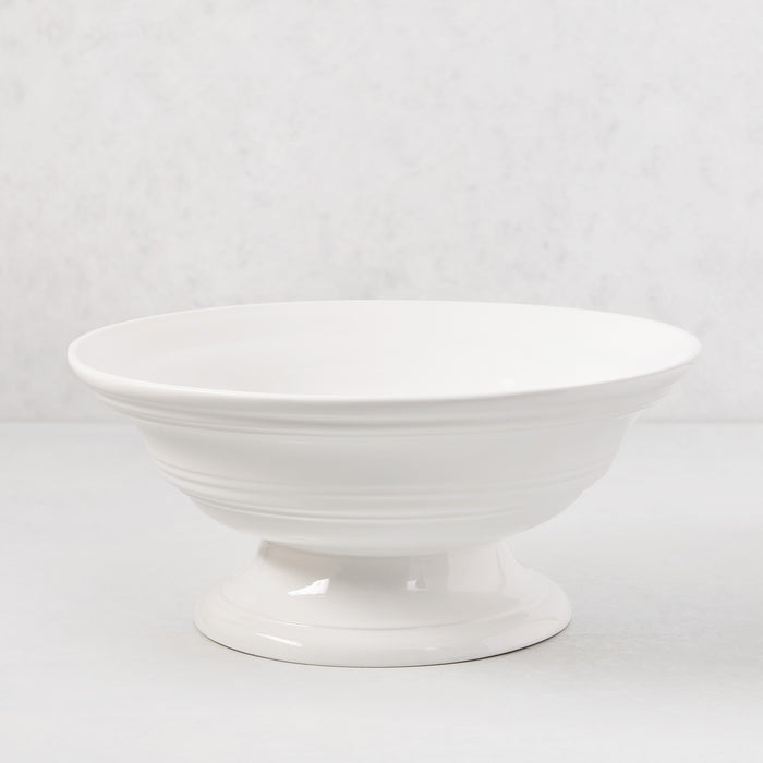 White ceramic footed bowl, 11.5" round, with a smooth glaze and subtle horizontal ridges.