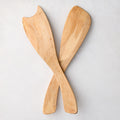 Hand-carved rustic spalted maple wood salad servers, light brown with unique grain, crossed on white.