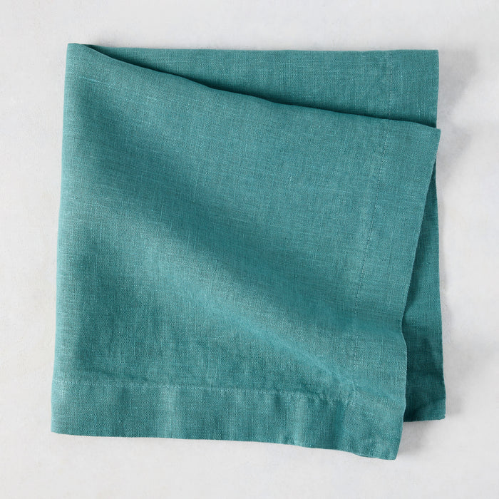 Sage HG Signature hand-dyed linen napkin, folded, showing earthy teal color and natural texture.