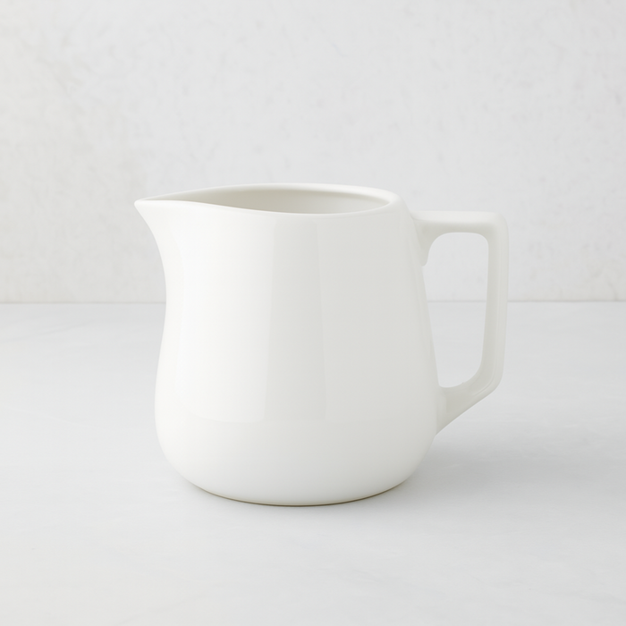 Small white ceramic milk pitcher with a simple, artisanal design.