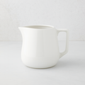 Small white ceramic milk pitcher with a simple, artisanal design.