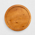 Small round natural reclaimed pine wood serving tray with raised rim and visible grain.