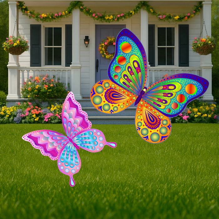 Two decorative butterfly garden signs in bright colors, a large blue and yellow butterfly and a small pink butterfly, displayed on a lawn in front of a house.