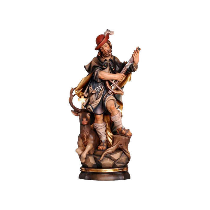 Sculpted wooden statue of St. Hubert in flowing hunting robes and hat, holding a crossbow and arrow, with an elk with a cross between its antlers sitting alongside of him.