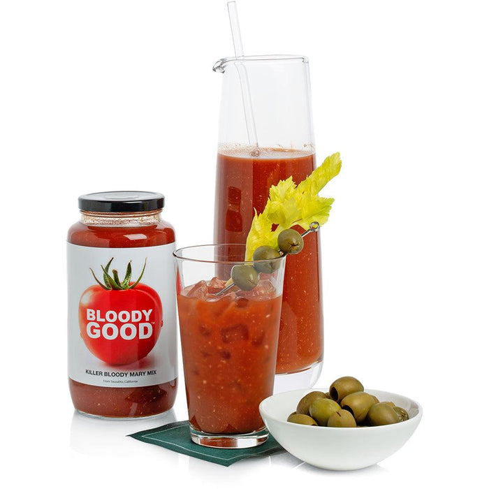 Bloody Mary mix jar, glass, and pitcher with celery and olives.