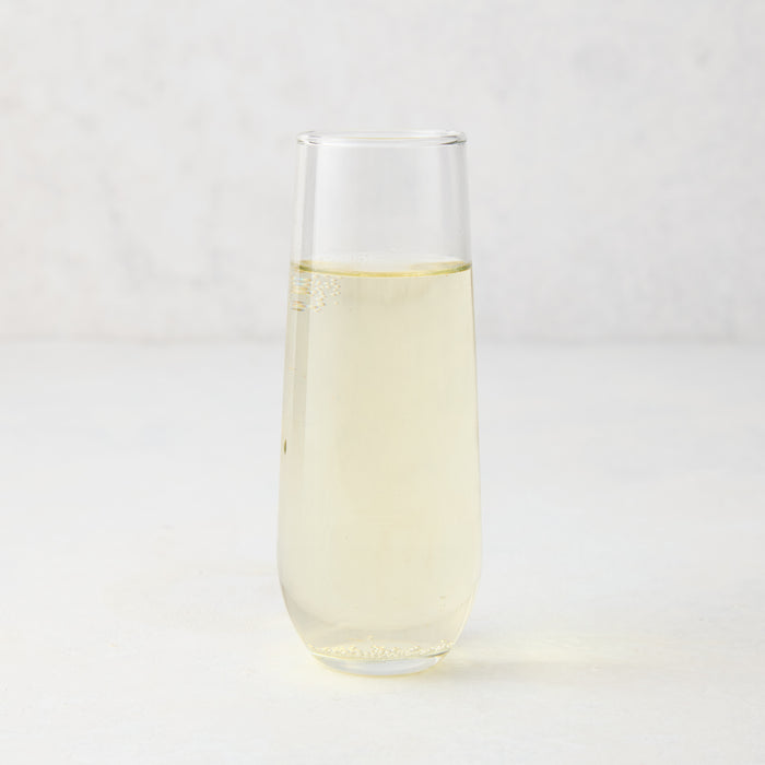 Clear Hudson Grace stemless champagne flute with sparkling light yellow liquid.