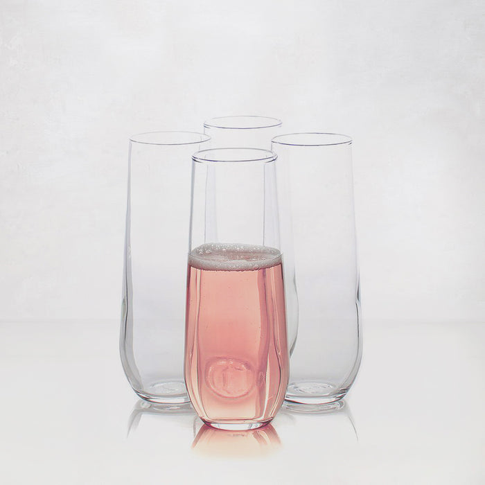 Four clear Hudson Grace stemless champagne flutes, one filled with pink sparkling wine.