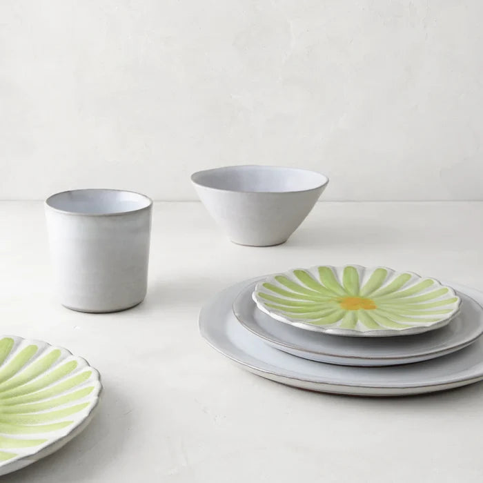 Stone grey terracotta mug, bowl, and plates, with two plates featuring a green and yellow daisy design.