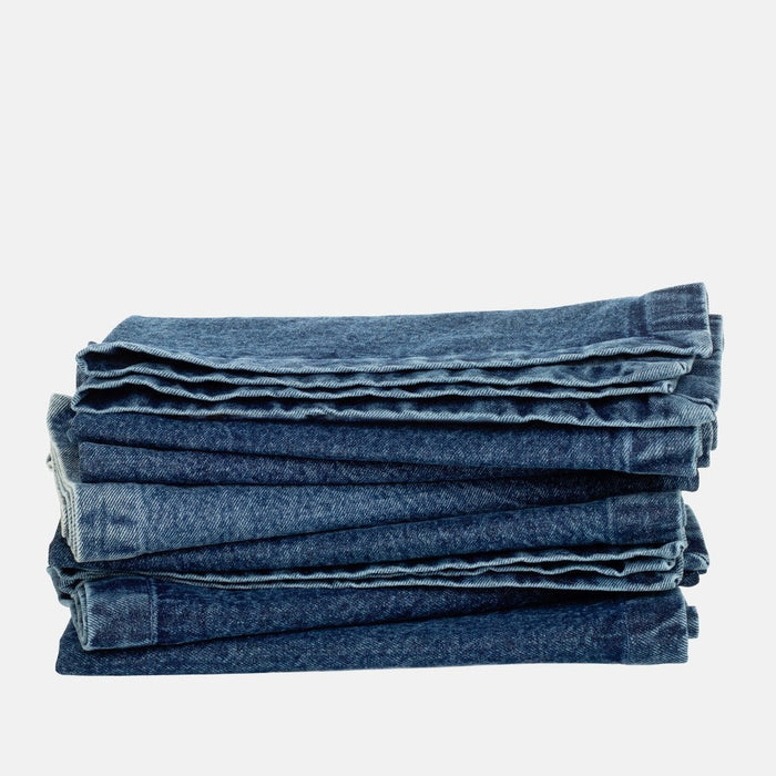 Stack of folded stonewashed blue denim napkins with single needle stitch, 20" square.
