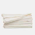 Stack of folded stonewashed white denim napkins, 20" square, with single needle stitch.