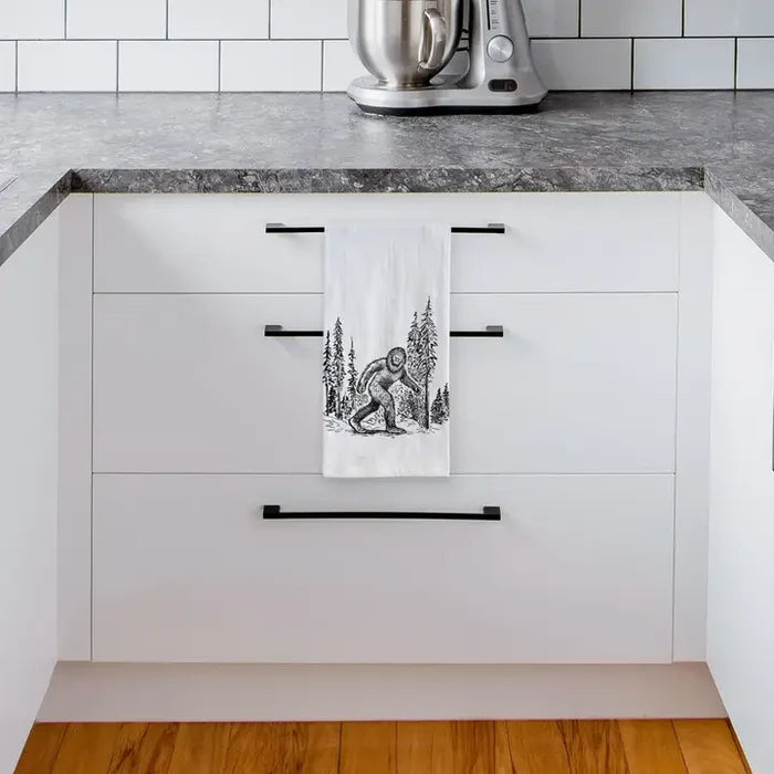 Kitchen with white cabinets, black handles, and a towel with a bear design hanging on one of the cabinets.