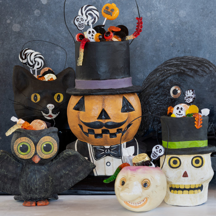 Handcrafted papier-mâché turnip candy bucket with distressed finish and eerie face, styled for Halloween decor.
