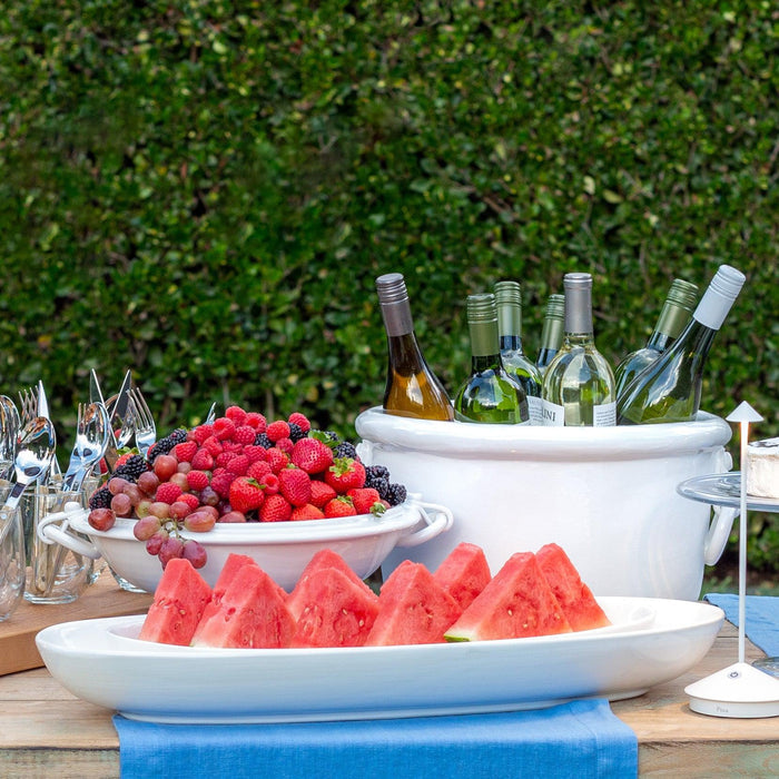 Torino Large Oval Ceramic Serving Platter with watermelon slices, white wine, and berries on a table.