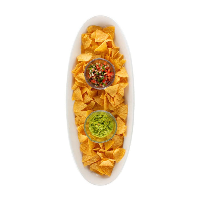 White oval ceramic serving platter filled with tortilla chips, guacamole, and salsa.