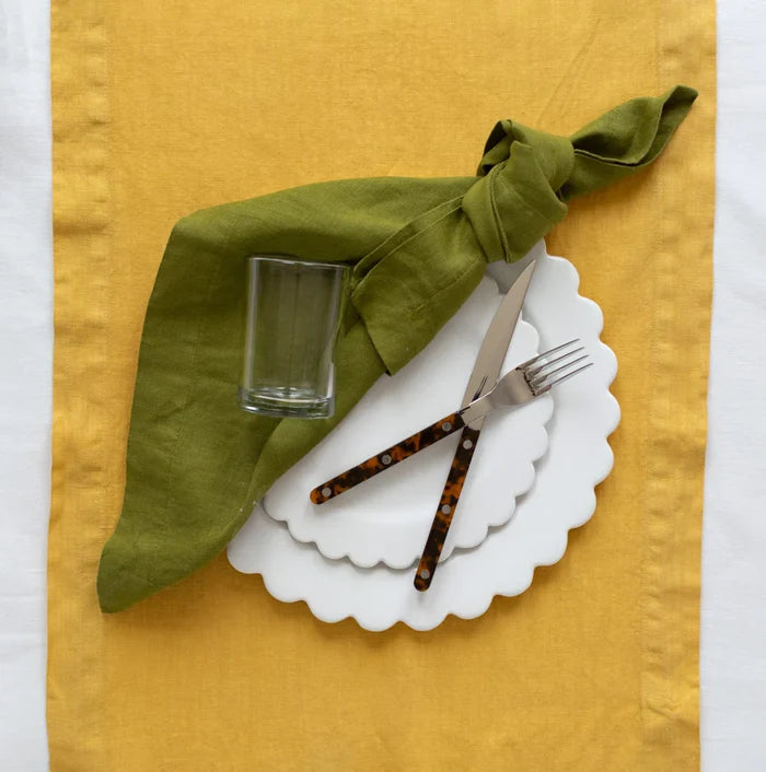 Tortoise Bistro 5-piece flatware set with stainless steel and tortoise acrylic handles on a white scalloped plate.