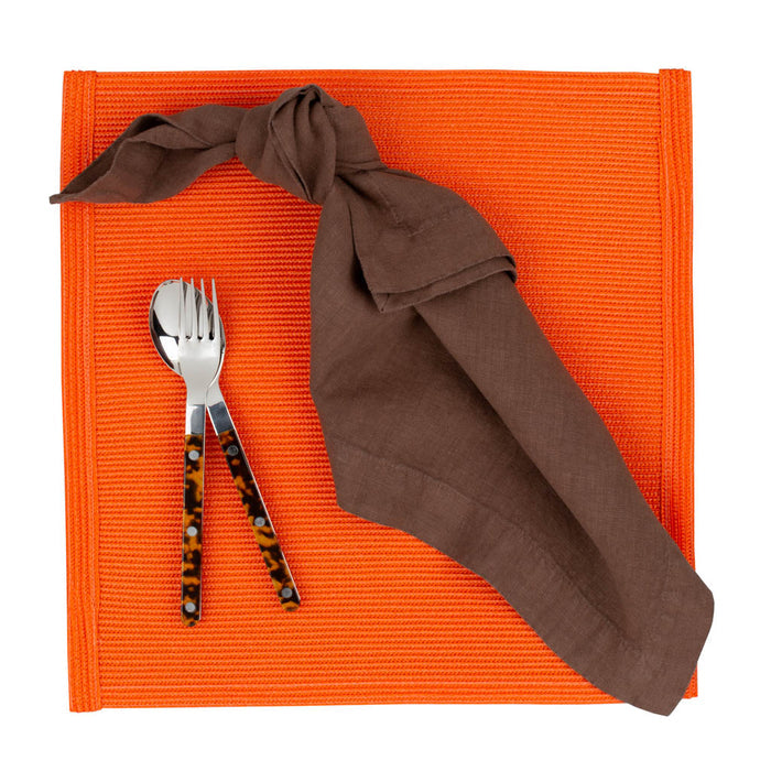 Tortoise Bistro 5-piece flatware set with stainless steel and acrylic handles on an orange placemat with a brown napkin.