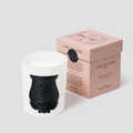 Trudon Rose Poivree Classic Scented Candle in a white glass vessel with a black emblem, beside a pink box.