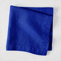 Ultramarine HG Signature hand-dyed 22" square linen napkin, folded, on a white background.