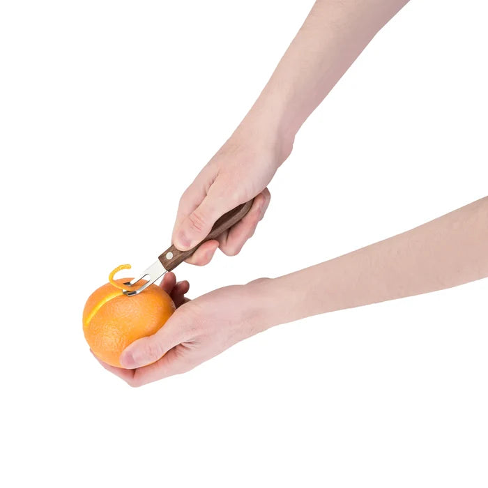 Hand using a walnut wood channel knife to peel a thin strip from an orange.