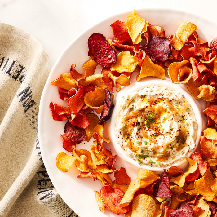 White ceramic 15"Dia chip and dip platter with colorful vegetable chips and a creamy dip.