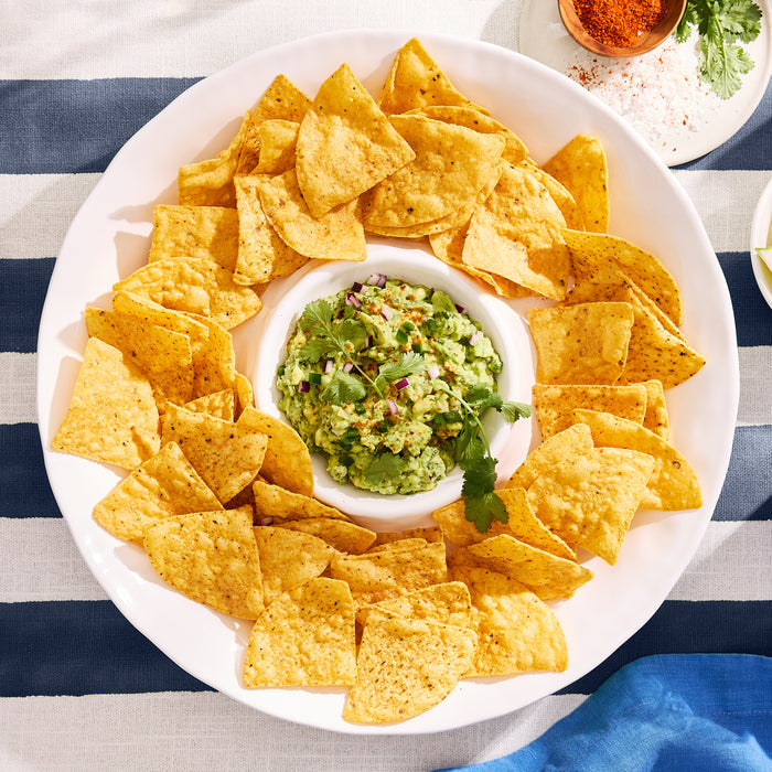 White ceramic 15"Dia chip and dip platter with a ruffled edge, filled with tortilla chips and guacamole.
