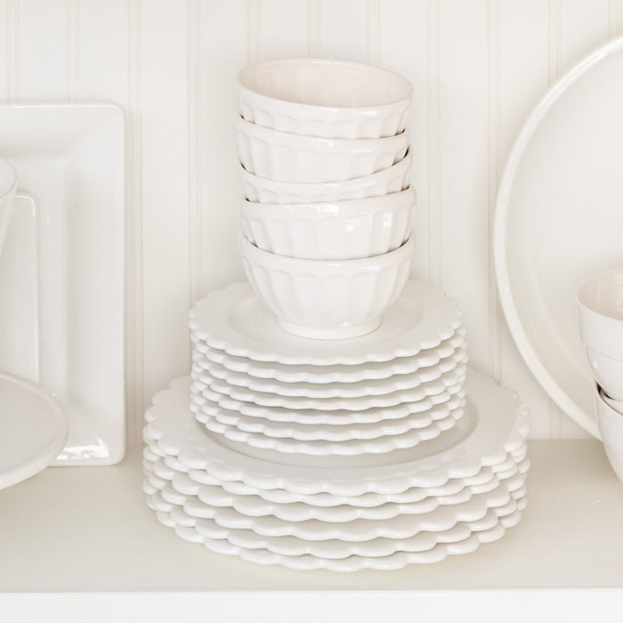 Stacked white ceramic latte bowls on scalloped plates.