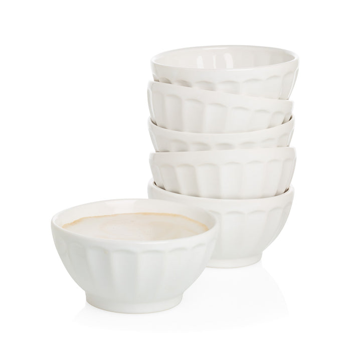Stack of five white ceramic latte bowls and one bowl filled with a light beverage.