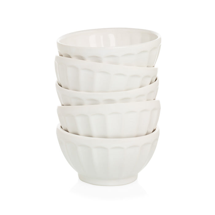 Stack of five creamy white ceramic latte bowls with fluted sides.